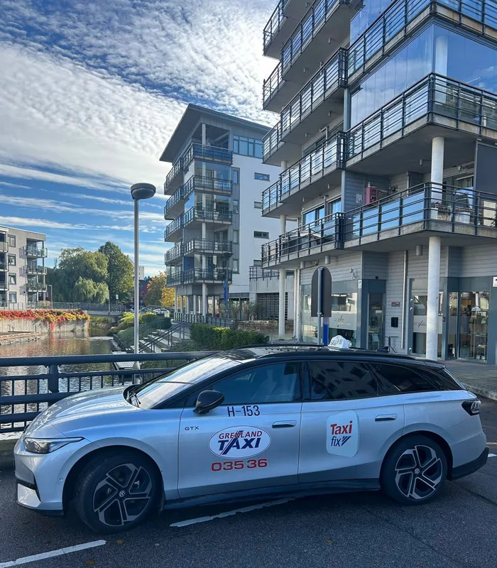 Sølvfarget elektrisk Grenland Taxi ved elvebredden i Skien
